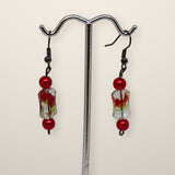 Fire Earrings with red beads and clear flame-pattern beads on black hooks, shown on a silver stand