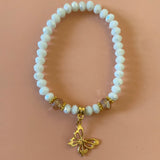 White bracelet with gold dangling butterfly